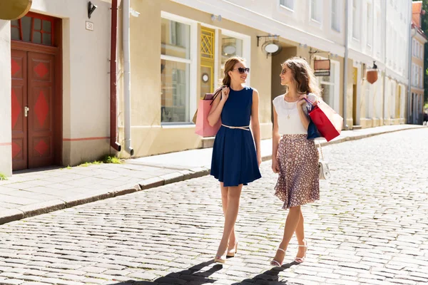 Happy women with shopping bags walking in city — Stock Photo, Image