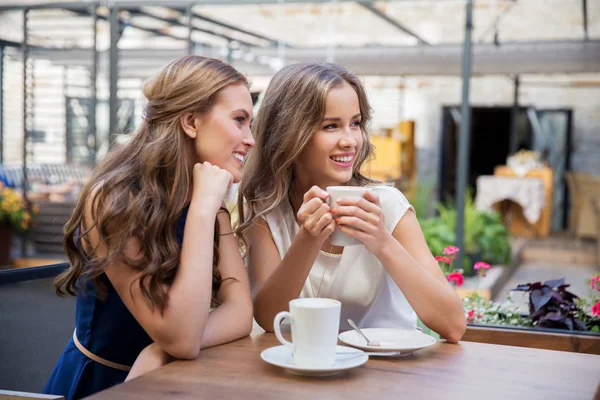 Smiling young women drinking coffee at street cafe — Stock Photo, Image