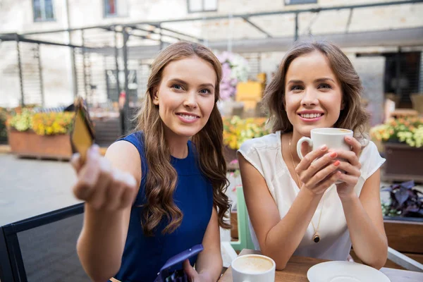 Young women paying for coffee at street cafe — Stock Photo, Image