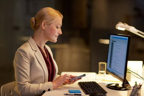 Mujer de negocios con teléfono inteligente en la oficina de noche —  Fotos de Stock