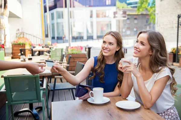 Молоді жінки платять за каву у вуличному кафе Стокове Фото