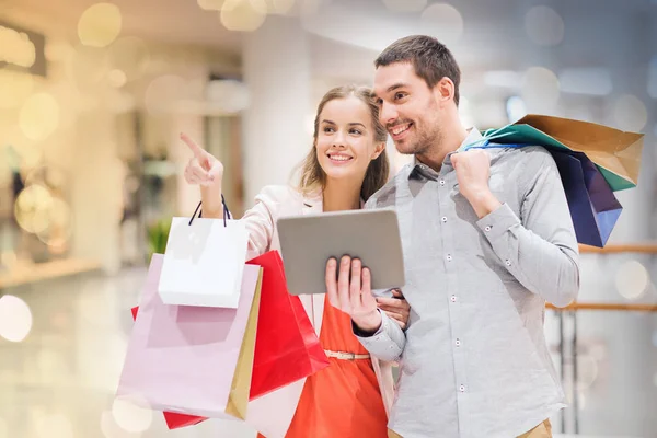 Casal com tablet pc e sacos de compras no shopping — Fotografia de Stock