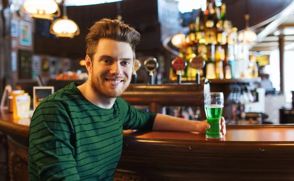 Человек пьет зеленое пиво в баре или пабе — стоковое фото