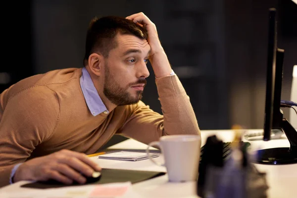 Trött man på bord på natt office — Stockfoto