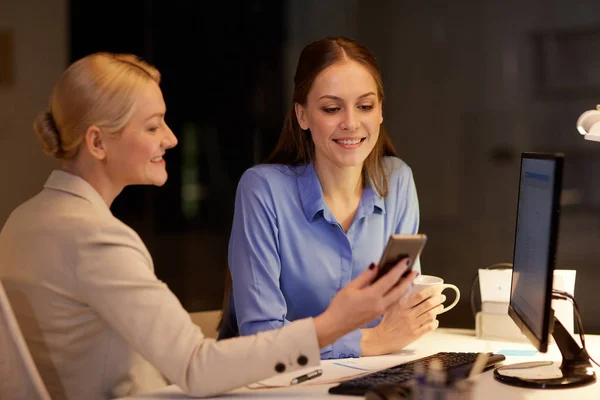 Forretningskvinner med smarttelefon sent på kveldskontoret – stockfoto