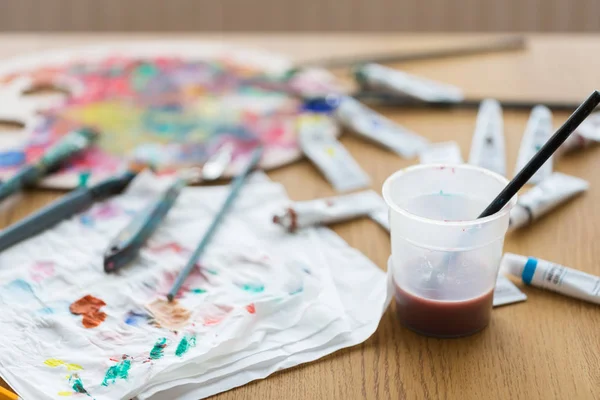Paintbrush soaking in cup of water on table — Stock Photo, Image