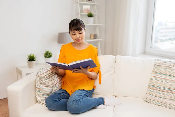 Sonriendo joven asiático mujer leyendo libro en casa — Foto de Stock