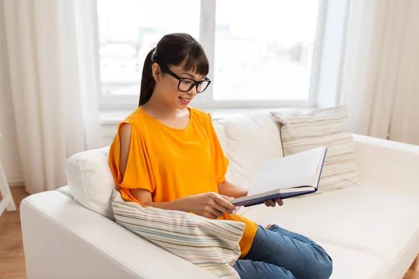 Joven asiático mujer en gafas lectura libro en casa — Foto de Stock