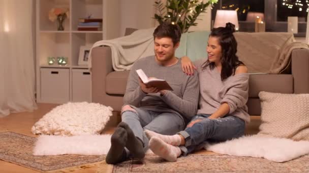 Feliz pareja leyendo libro en casa — Vídeos de Stock