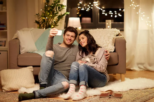 Casal feliz tomando selfie por smartphone em casa — Fotografia de Stock