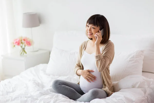 Heureuse femme enceinte appelant sur smartphone à la maison — Photo