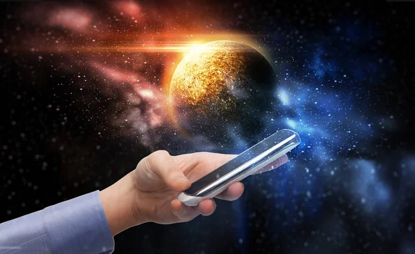 Mão segurando smartphone sobre planeta no espaço — Fotografia de Stock