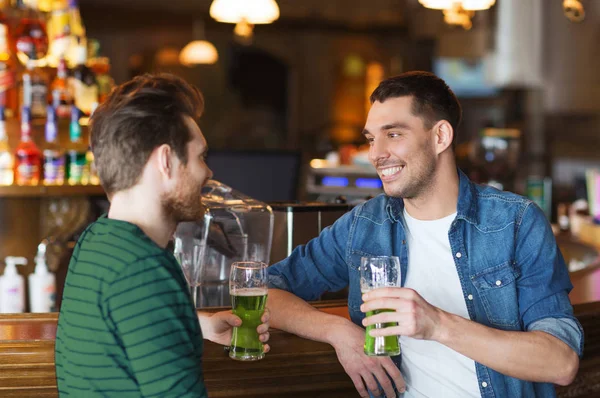 Друзья мужчины пьют зеленое пиво в баре или пабе — стоковое фото