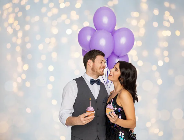 Щаслива пара з повітряними кулями і кексами на вечірці — стокове фото