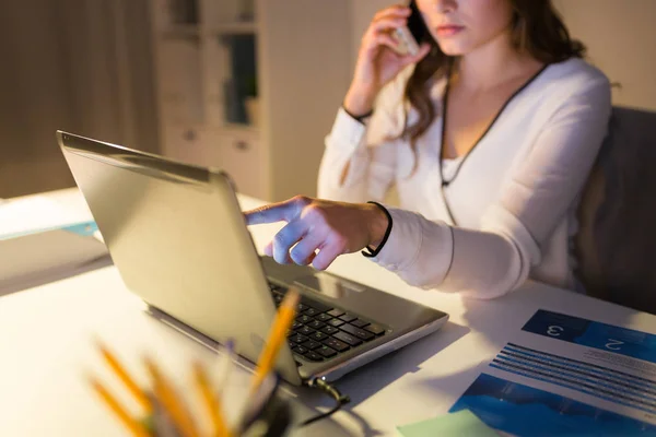 Kvinna med bärbar dator ringer på smartphone på kontoret — Stockfoto