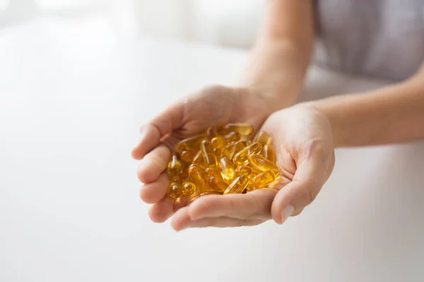 Mani che tengono le capsule di olio di fegato di merluzzo — Foto Stock