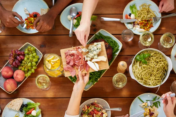 Grupo de pessoas comendo à mesa com alimentos — Fotografia de Stock