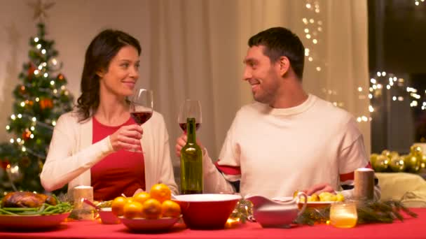 Ευτυχισμένο ζευγάρι πίνοντας κόκκινο κρασί στο χριστουγεννιάτικο δείπνο — Αρχείο Βίντεο