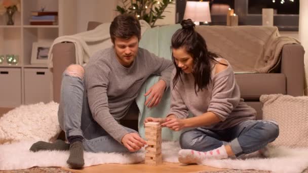 Ευτυχισμένο ζευγάρι παίζει μπλοκ στοίβαγμα παιχνίδι στο σπίτι — Αρχείο Βίντεο