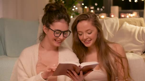 Happy female friends reading book at home — Stock Video