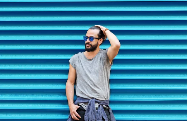 Hombre en gafas de sol posando sobre la pared azul acanalada —  Fotos de Stock