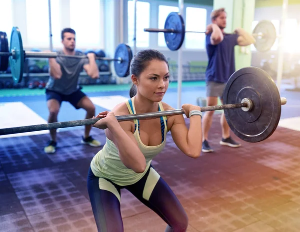 Träningsgrupp med skivstång och vikter på gym — Stockfoto