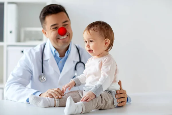 Happy baby dívka u doktora na den červený nos — Stock fotografie