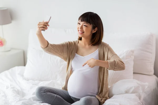 妊娠中の女性がスマート フォンを自宅で selfie を取って — ストック写真