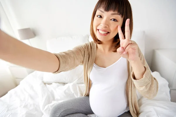 Zwangere vrouw nemen selfie in bed thuis — Stockfoto