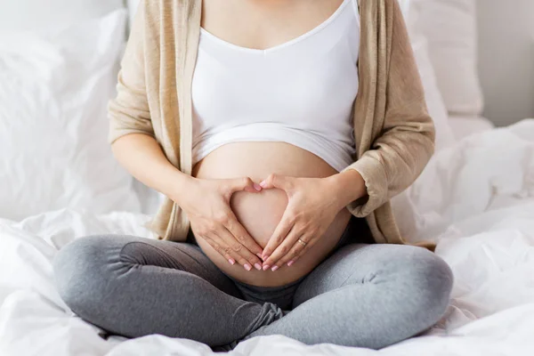 ベッドで幸せな妊娠中の女性、心ジェスチャー — ストック写真