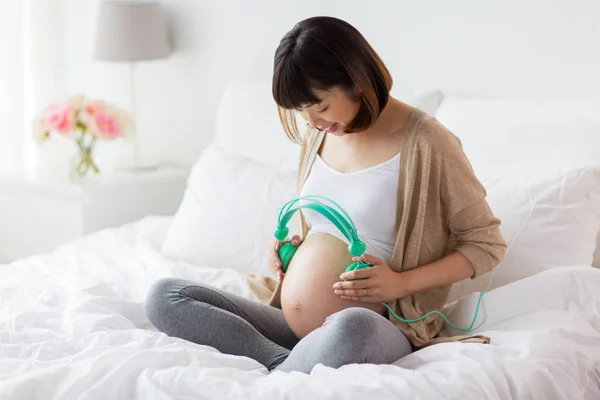 Happy pregnant woman with headphones at home — Stock Photo, Image