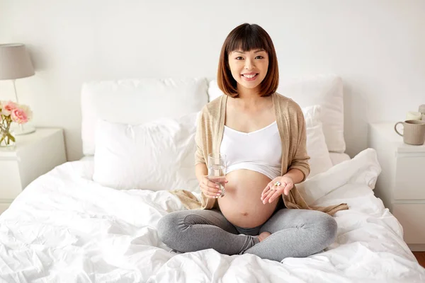 Evde yatakta haplarla mutlu hamile kadın — Stok fotoğraf
