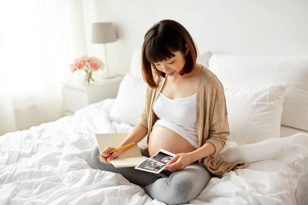 Mulher grávida com imagem de ultra-som fetal em casa — Fotografia de Stock