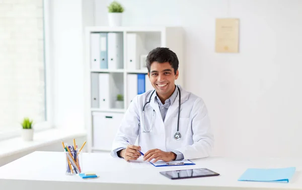 Zufriedener Arzt mit Klemmbrett in Klinik — Stockfoto