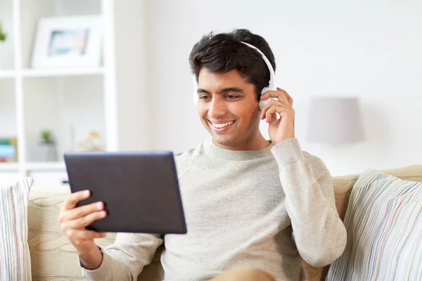 Man in telefoons met tablet pc luisteren naar muziek — Stockfoto