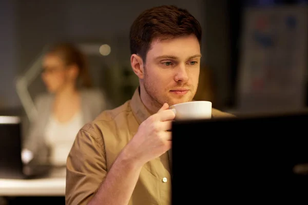 Homme avec ordinateur portable et café travaillant au bureau de nuit — Photo