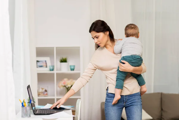 Мать с ребенком и ноутбук работает на дому — стоковое фото