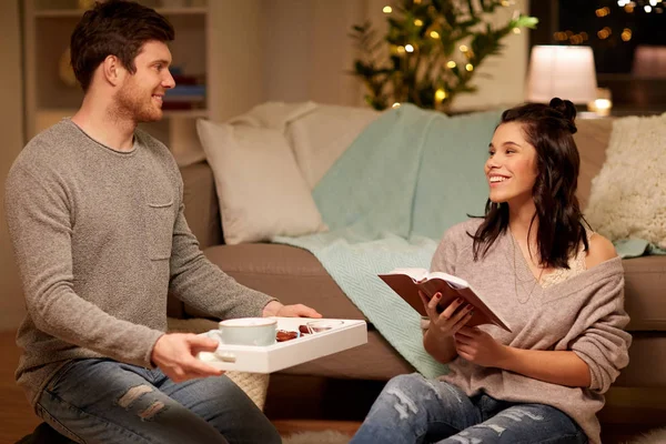 Happy couple with book and food at home — Stock Photo, Image
