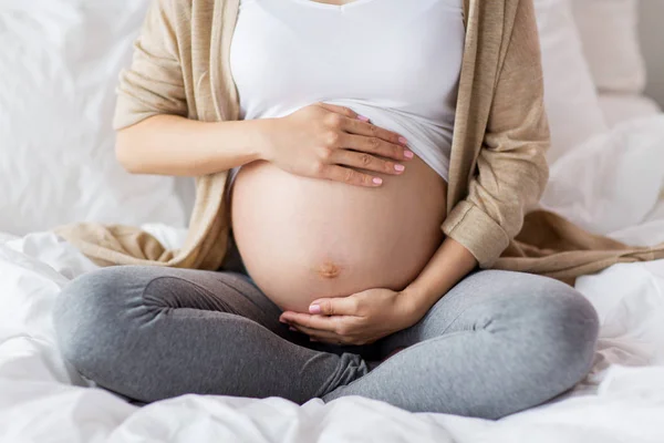 Těhotná žena s holé břicho seděl v posteli — Stock fotografie