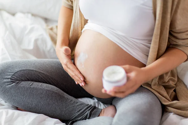 Nahaufnahme einer schwangeren Frau, die den Bauch eincremt — Stockfoto