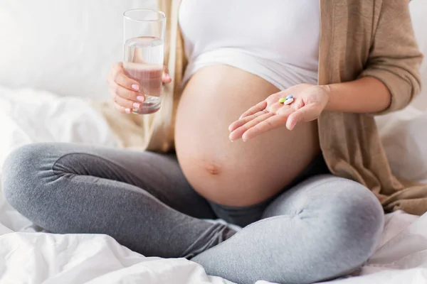 Close-up de mulher grávida com pílulas na cama — Fotografia de Stock