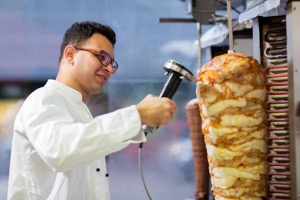 Chef rebanando carne doner de escupir en la tienda de kebab —  Fotos de Stock