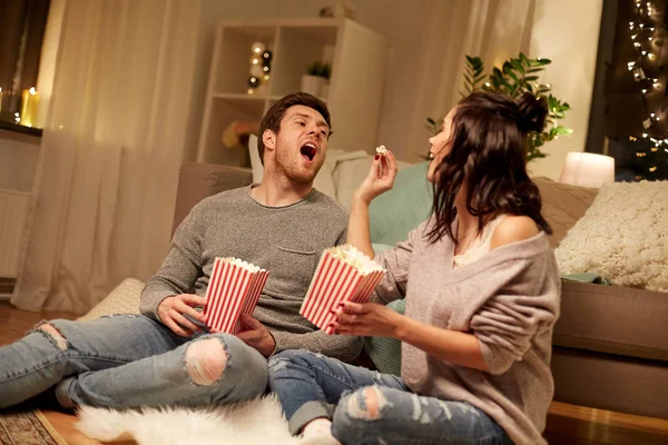 Casal feliz comer pipocas em casa — Fotografia de Stock