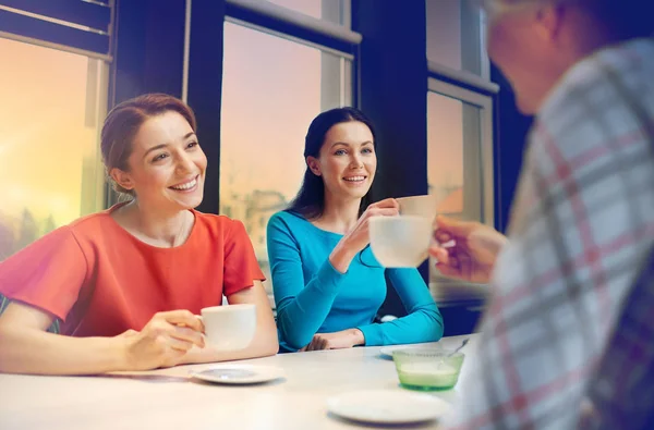 Happy young women drinking tea or coffee at cafe — Stock Photo, Image