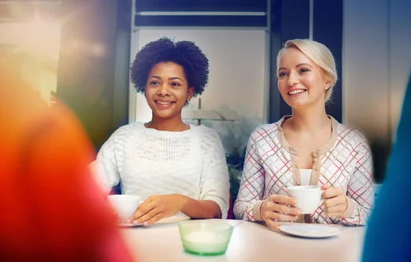 Happy young women drinking tea or coffee at cafe — Stock Photo, Image