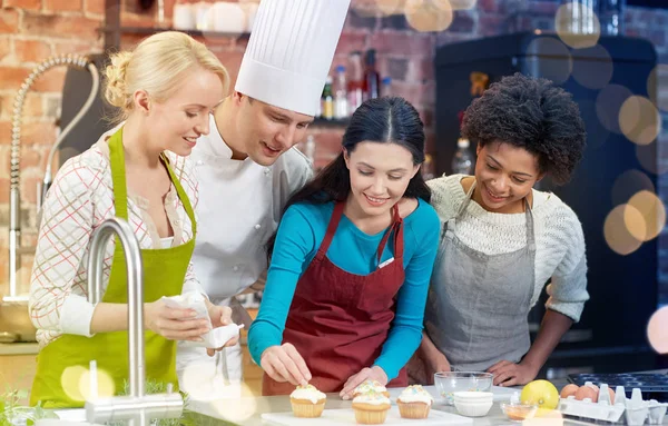 Glückliche Frauen und Koch kochen in der Küche — Stockfoto