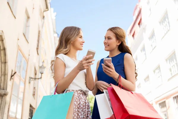 Šťastné ženy s nákupní tašky a smartphone — Stock fotografie