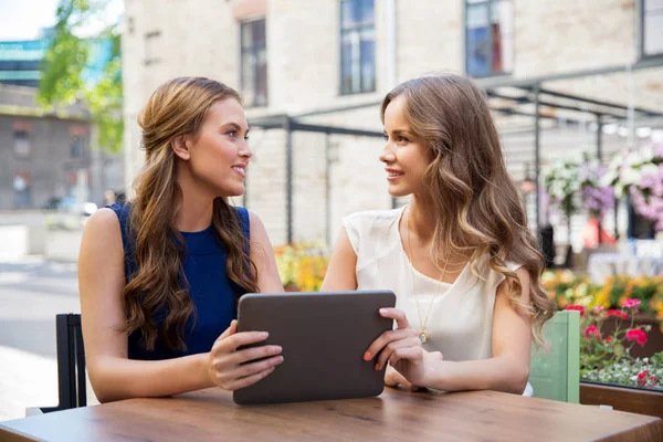 Mulheres jovens felizes com tablet pc no café ao ar livre — Fotografia de Stock