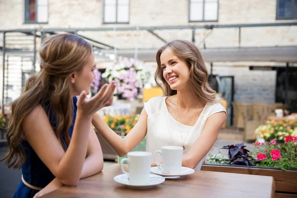 Счастливые молодые женщины пьют кофе в кафе на открытом воздухе — стоковое фото