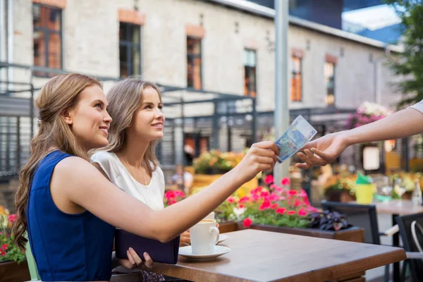 Молодые женщины платят за кофе в уличном кафе — стоковое фото